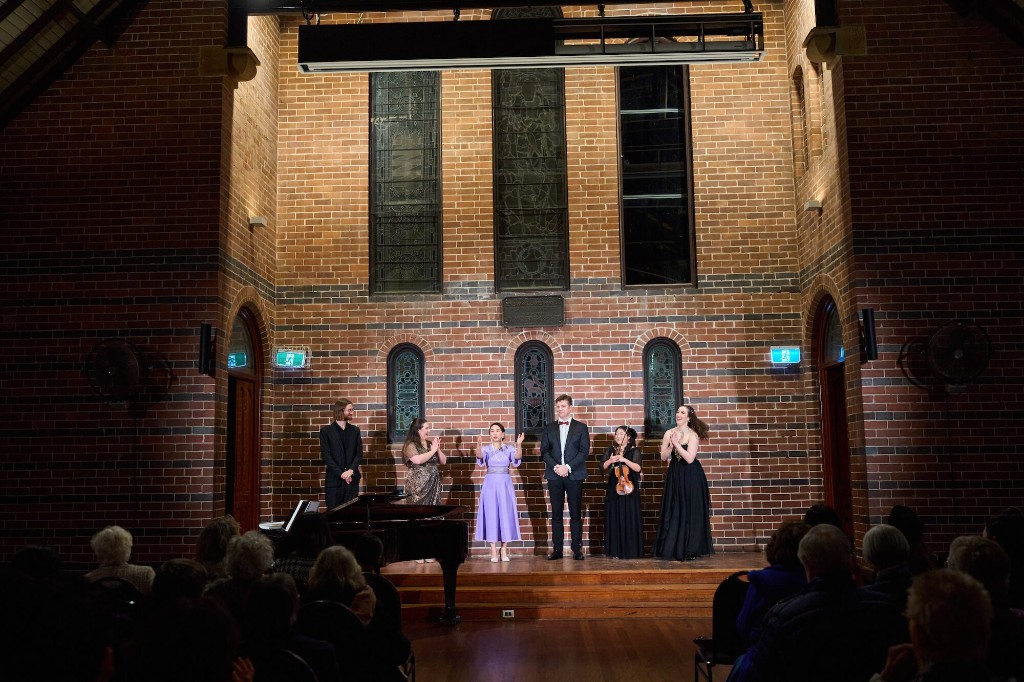 Aleta Shang taking a curtain call with fellow musicians in a brick hall